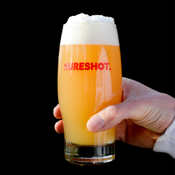 A hand holding a glass of delicious Sureshot beer
