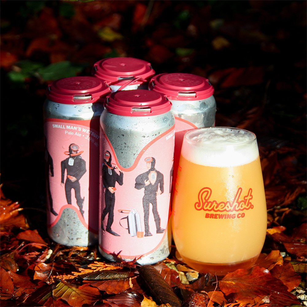 Cans of Shureshot and a glass of beer amongst autumn leaves
