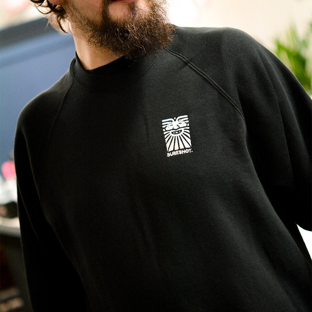 A beautifully-modelled black sweatshirt, bearing a white Sureshot logo on the chest